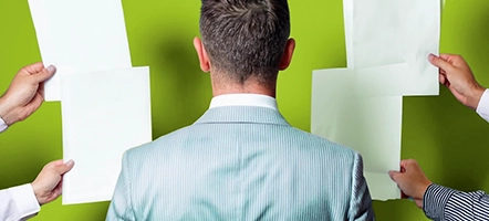 A man stands in the center of the picture, documents are handed to him from the sides